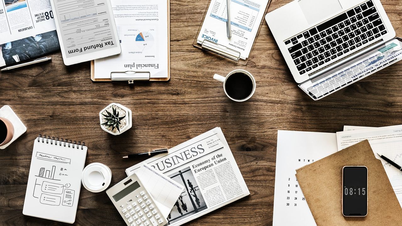 Desk spread with charts, a laptop and a business newspaper