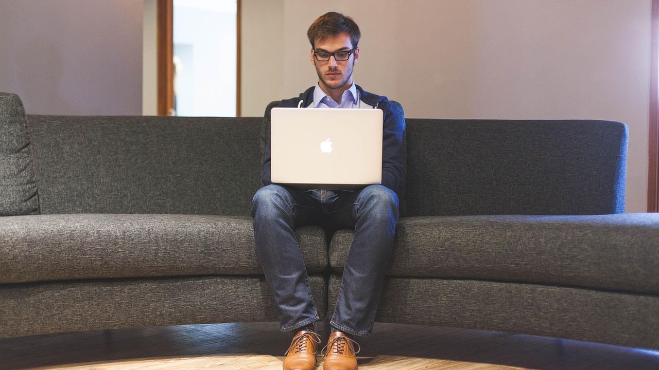 Man working on a laptop on a sofa at home