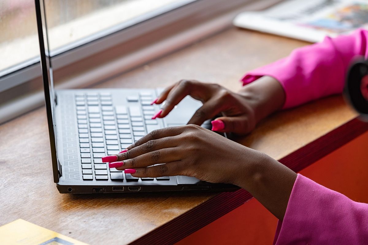 Woman typing on a laptop at a wooden table