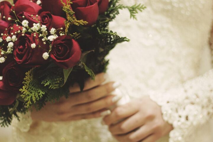 Bride holding a bouquet of deep red roses