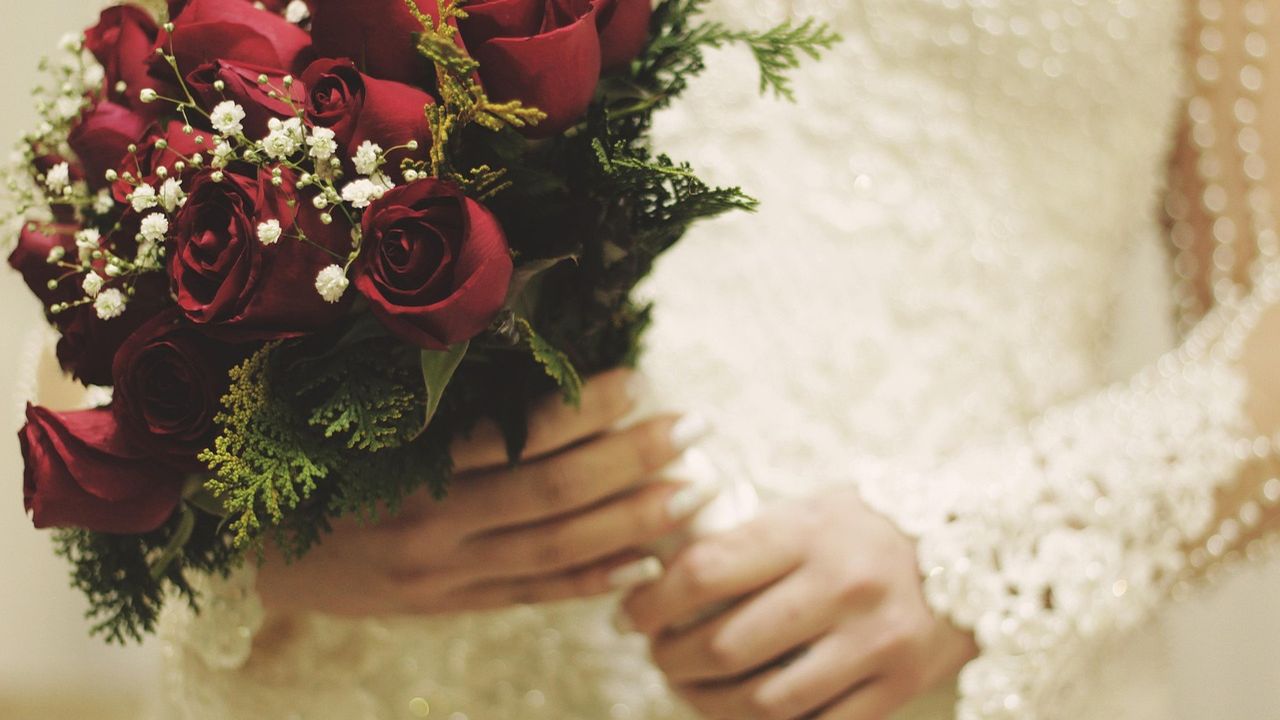 Bride holding a bouquet of deep red roses
