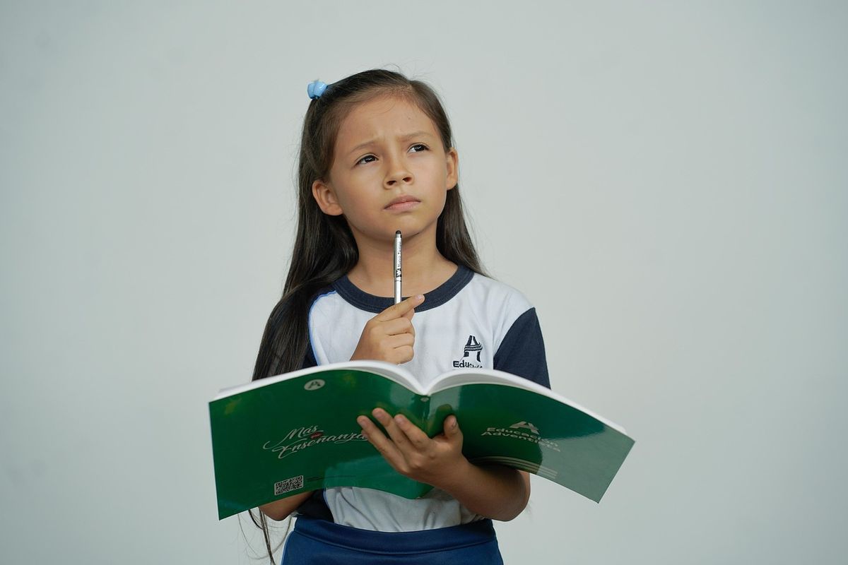 Schoolgirl thinking while holding a textbook